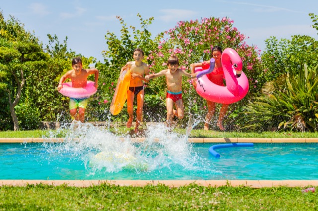 Cute kids jumping in swimming pool with swim rings