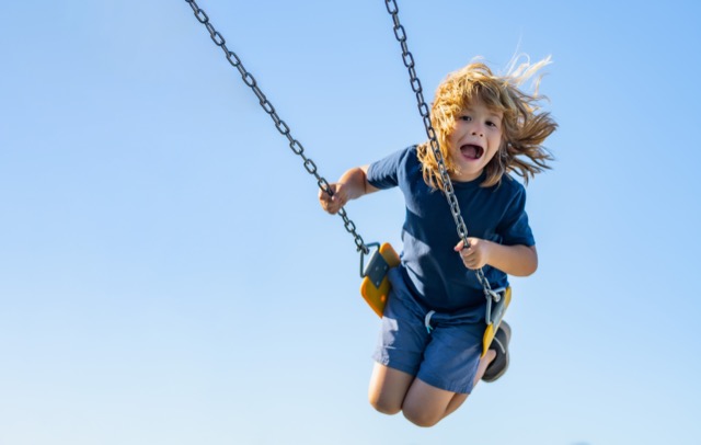 Swinging on playground. Funny kid on swing. Little boy swinging on playground. Happy cute excited child on swing. Cute child swinging on a swing. Crazy playful child swinging very high.